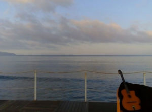 chitarra su pontile con sfondo mare e nuvole